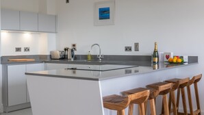 A modern kitchen with a central island, bar stools, and a bottle of champagne.
