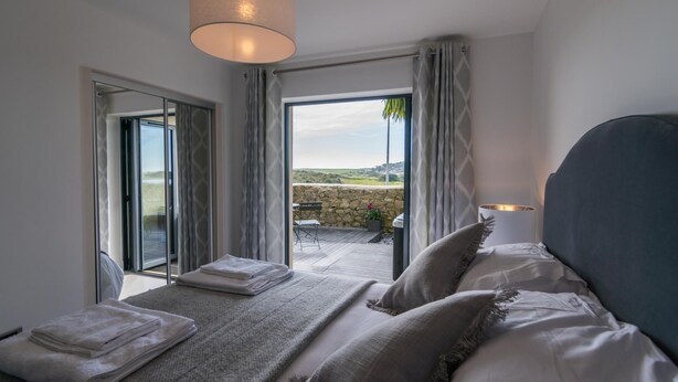 A bedroom with a bed, a view of the outdoors, and a large window.