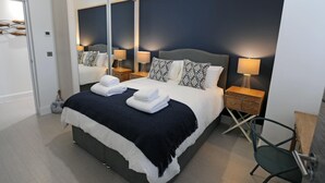 Une chambre d’hôtel moderne avec un grand lit, deux tables de chevet, une chaise et un miroir.