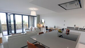 Une cuisine moderne dotée d’un îlot central, d’un coin repas avec un canapé et de grandes fenêtres offrant une vue dégagée.