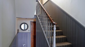 Un escalier avec des rampes en bois et des marches recouvertes d’une moquette à rayures.