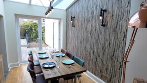 Un coin repas avec une table en bois dressée pour six personnes, entourée de chaises.