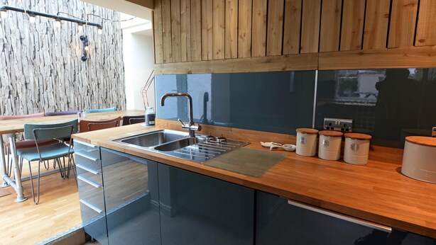 Une cuisine moderne avec des meubles en bois, un évier encastré et un coin repas comprenant des chaises et une table.