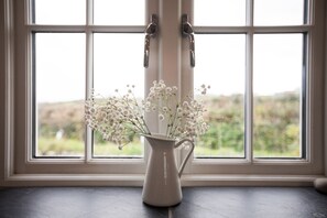 Een witte vaas met bloemen op een vensterbank.