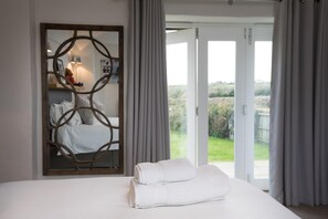 Een slaapkamer met een bed, een spiegel en uitzicht op de omgeving.