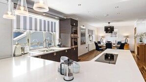 A modern kitchen with a large island, stainless steel appliances, and pendant lighting. - Oaktree Lodge - Luxury Cottage Hot Tub Sea Views (Saundersfoot)