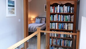 Un escalier menant à une chambre à coucher où se trouve une grande bibliothèque en bois remplie de livres.