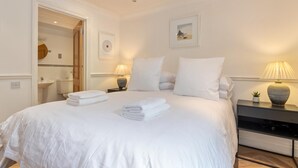 A hotel room with a large bed, two bedside tables, a nightstand, a mirror, and a framed picture on the wall.