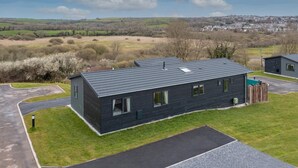 A modern two-story house with a dark exterior, a flat roof, and a small front yard. - Valley View Lodge - Luxury Lodge Hot Tub Close to Beach (Tenby)