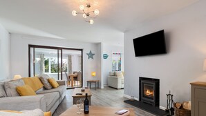 Ein modernes Wohnzimmer mit Sofa, Couchtisch, Kamin und einem an der Wand befestigten Fernseher.