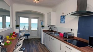 Eine moderne Küche mit Meerblick, Holzboden und einem Essbereich mit Stühlen und Tisch.
