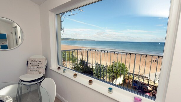 Ein Badezimmer mit großem Fenster zum Strand, einer Toilette und einem Spiegel.