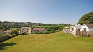 A residential area with houses, a grassy lawn, and a view of a distant town. - Amber Cottage - Luxury Cottage Hot Tub Sea Views and Log Burner (Saundersfoot)
