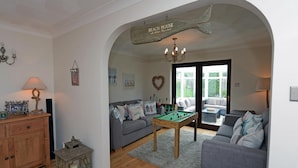 A cozy living room with a pool table, a sofa, and a couch. There's a wooden cabinet and a lantern on the left. - Swallow Dale - Large Pet Friendly Cottage (Saundersfoot)