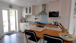 A modern kitchen with white cabinets, a wooden countertop, a gas stove, and a microwave.