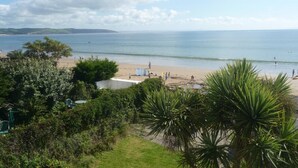 A coastal view with a beach, ocean, and distant hills.