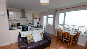 A compact living space with a kitchenette, a dining area, and a balcony with a view.