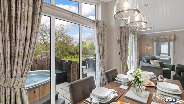 Un espace repas avec un jacuzzi, une table dressée pour le repas et une vue sur l’extérieur.