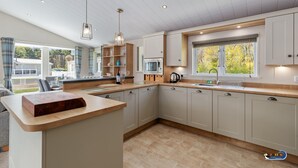 Une cuisine moderne dotée d’un plan de travail en bois, d’appareils électroménagers intégrés et d’une grande fenêtre qui laisse entrer la lumière naturelle.