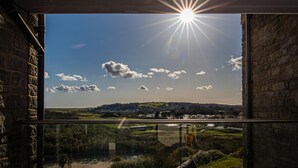 A room with a large window offering a view of a landscape with hills and a village. - Apartment 8 Waterstone House - Luxury Apartment Sea Views Pet Friendly (Tenby)