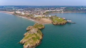 An aerial view of Waterstone APPTS, featuring a coastal town with buildings along the shore, a sandy beach, and rocky outcrops in the water. - Apartment 8 Waterstone House - Luxury Apartment Sea Views Pet Friendly (Tenby)