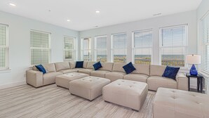 A spacious living room with a sectional sofa, ottomans, and a lamp. - THE OCEANFRONT GRAND RESORT: 17 BR Luxury with Unmatched Views+ALL THE AMENITIES (North Myrtle Beach)