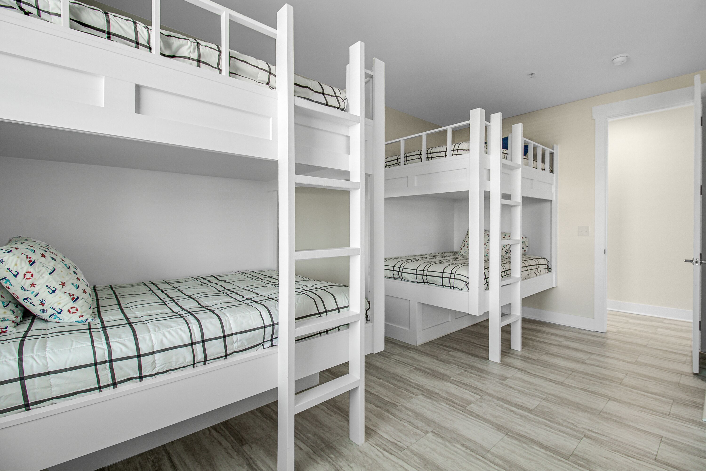 A room with bunk beds, wooden flooring, and a door.