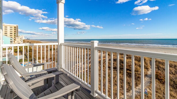 A wooden deck with a railing overlooking a beach with a clear sky. - Spectacular Oceanfront HOME Large Media&Game Room 12 bed 12 bath OVERSIZED POOL (North Myrtle Beach)