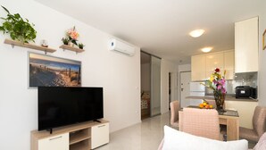 A modern living room with a flat-screen TV, a sofa, and a dining area with a table and chairs. - A2 - Modern apt With the Terrace & sea View (Split)