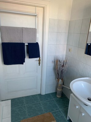 Bañera con ducha, toallas, jabón, papel higiénico