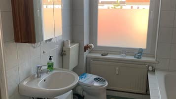 Bañera con ducha, toallas, jabón, papel higiénico