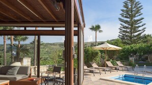 A covered outdoor area with a pool, lounge chairs, and a view of the surrounding landscape. - Kipo paradiso villa, pool,spa,massage,yoga,gym (Kyrianna)