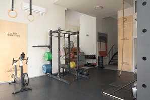A gym with a squat rack, weight plates, a stationary bike, and a pull-up bar.