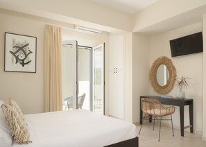 A bedroom with a bed, a desk, a chair, a television, and a door leading to an outdoor area.