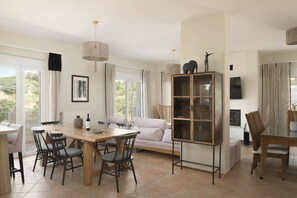 A dining area with a wooden table, chairs, a glass cabinet, and a sofa. - Kipo paradiso villa, pool,spa,massage,yoga,gym (Kyrianna)
