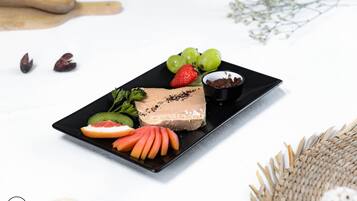 A dessert plate with chocolate mousse, strawberries, grapes, and a small bowl of chocolate shavings.