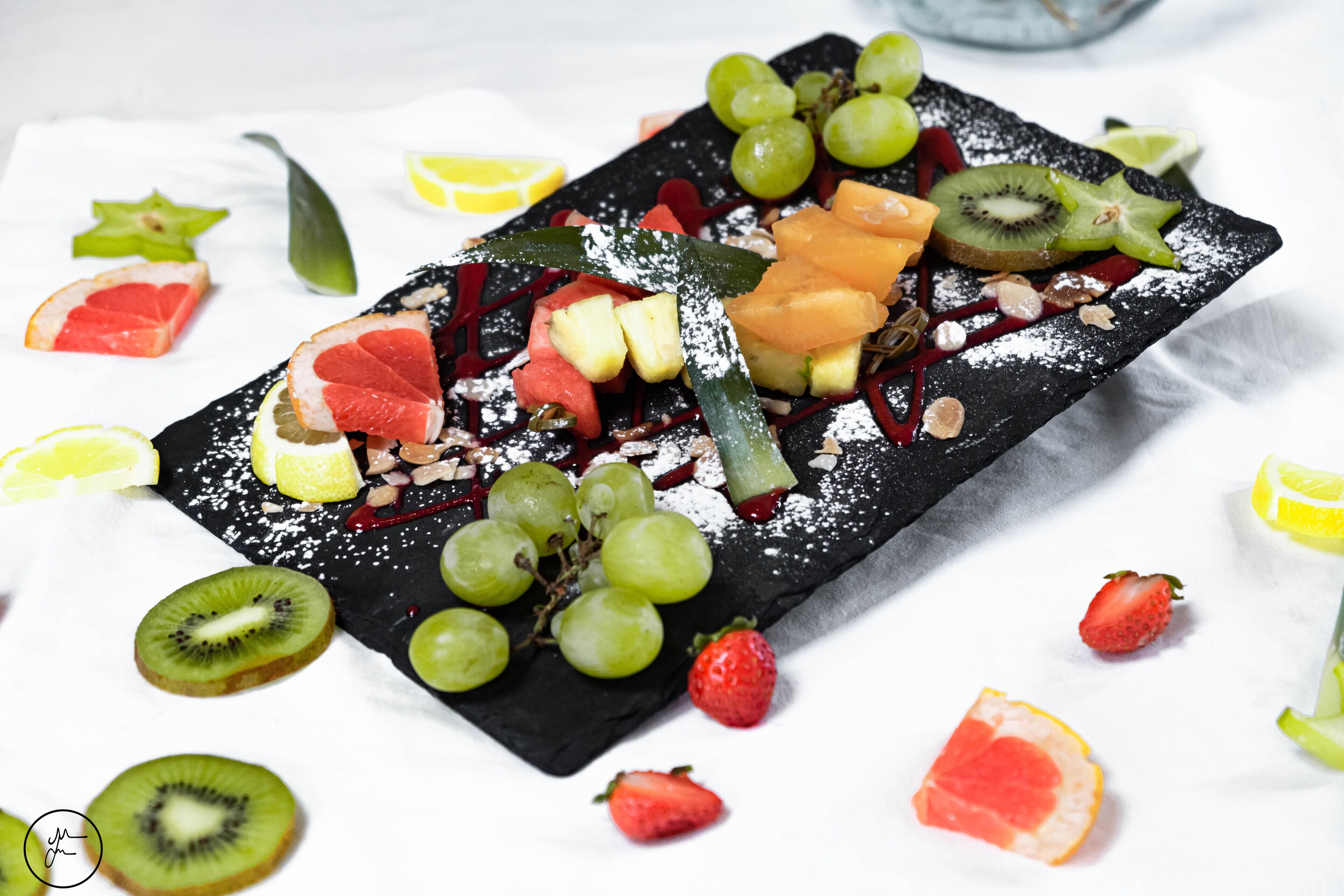 Una bandeja de frutas y nueces sobre una tabla de pizarra negra.