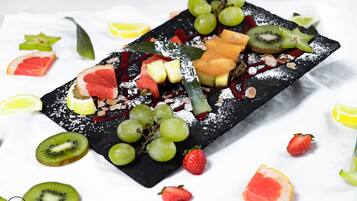 Una bandeja de frutas y nueces sobre una tabla de pizarra negra.