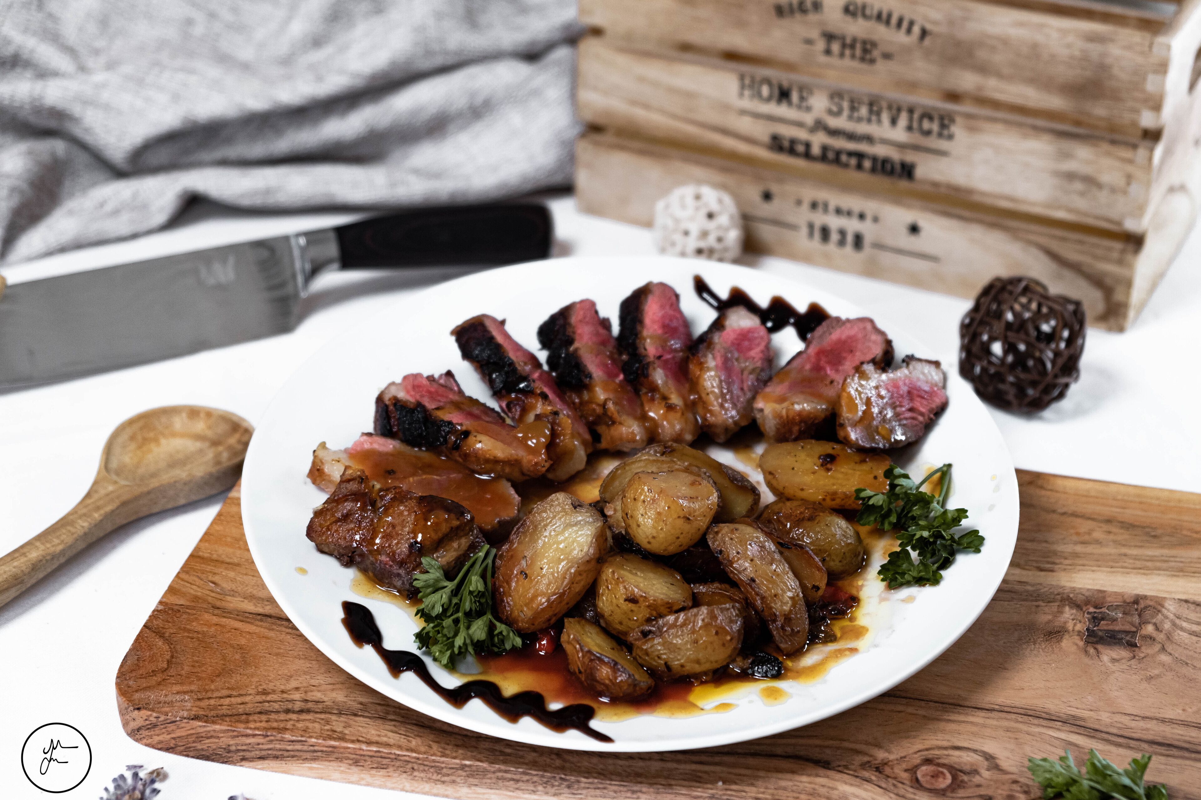 Een bord eten met steak en aardappelen op een houten tafel.