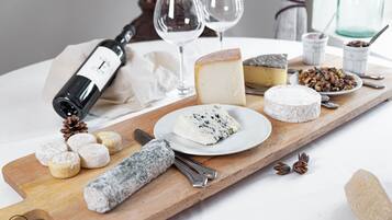A wooden board with various cheeses, a bottle of wine, and a rolling pin.