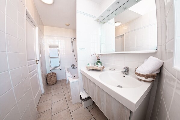 A modern bathroom with white tiles, a large mirror, a sink, and a shower. - La Bastide Cabezac (Bize-Minervois)
