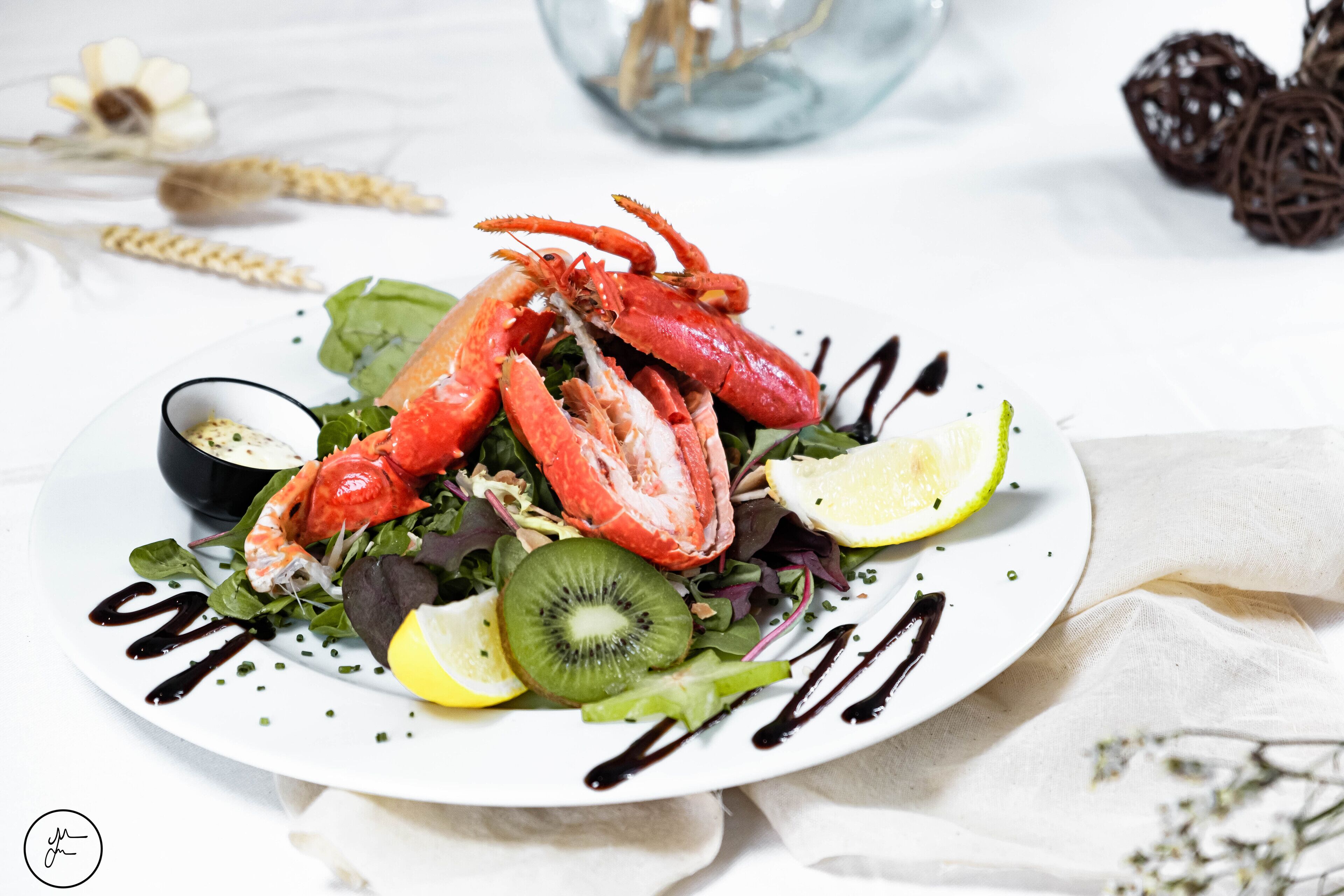 Ensalada de langosta con limón y kiwi sobre un plato blanco.