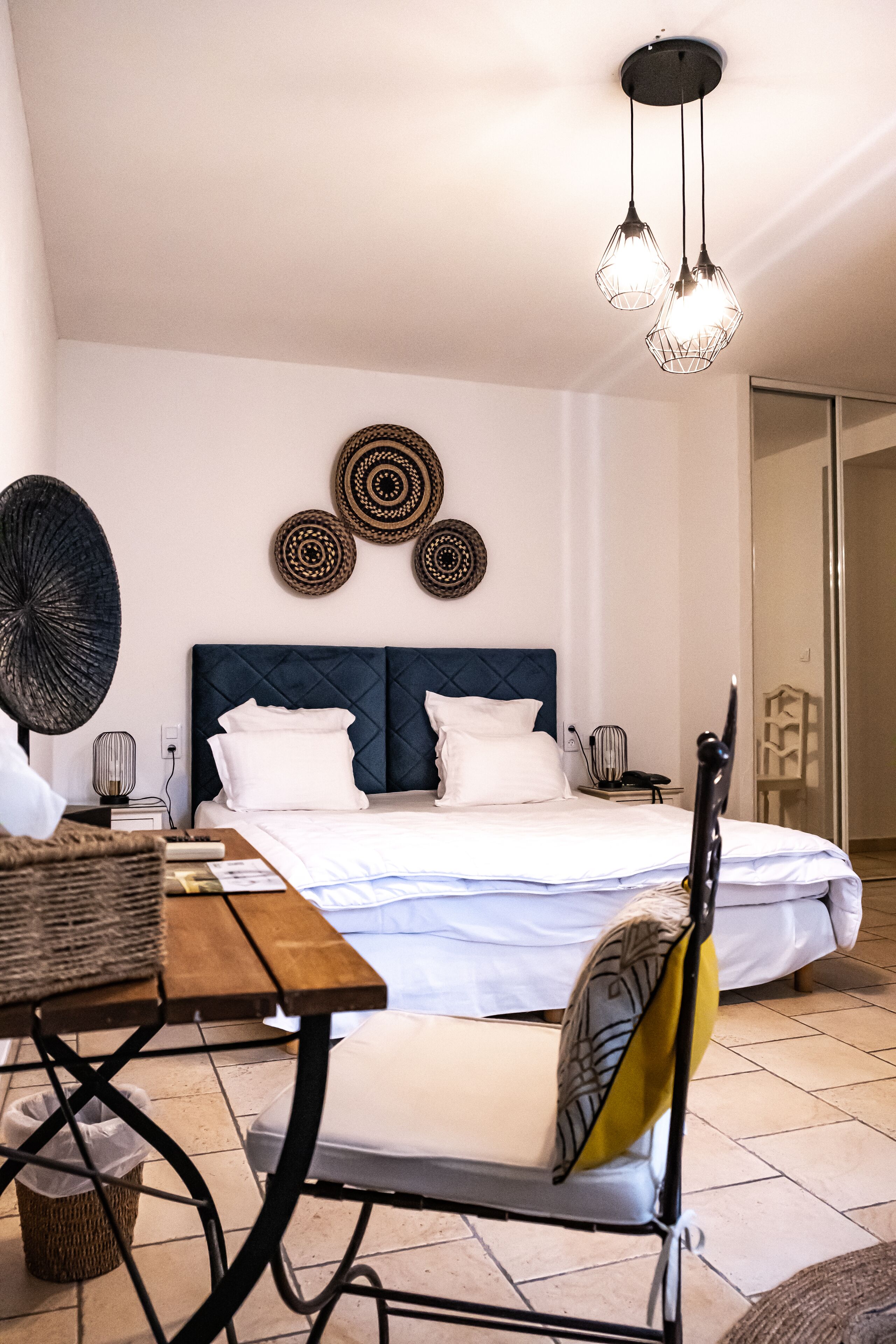 Un dormitorio con cama, mesita de noche, lámpara, decoración en la pared y una silla.