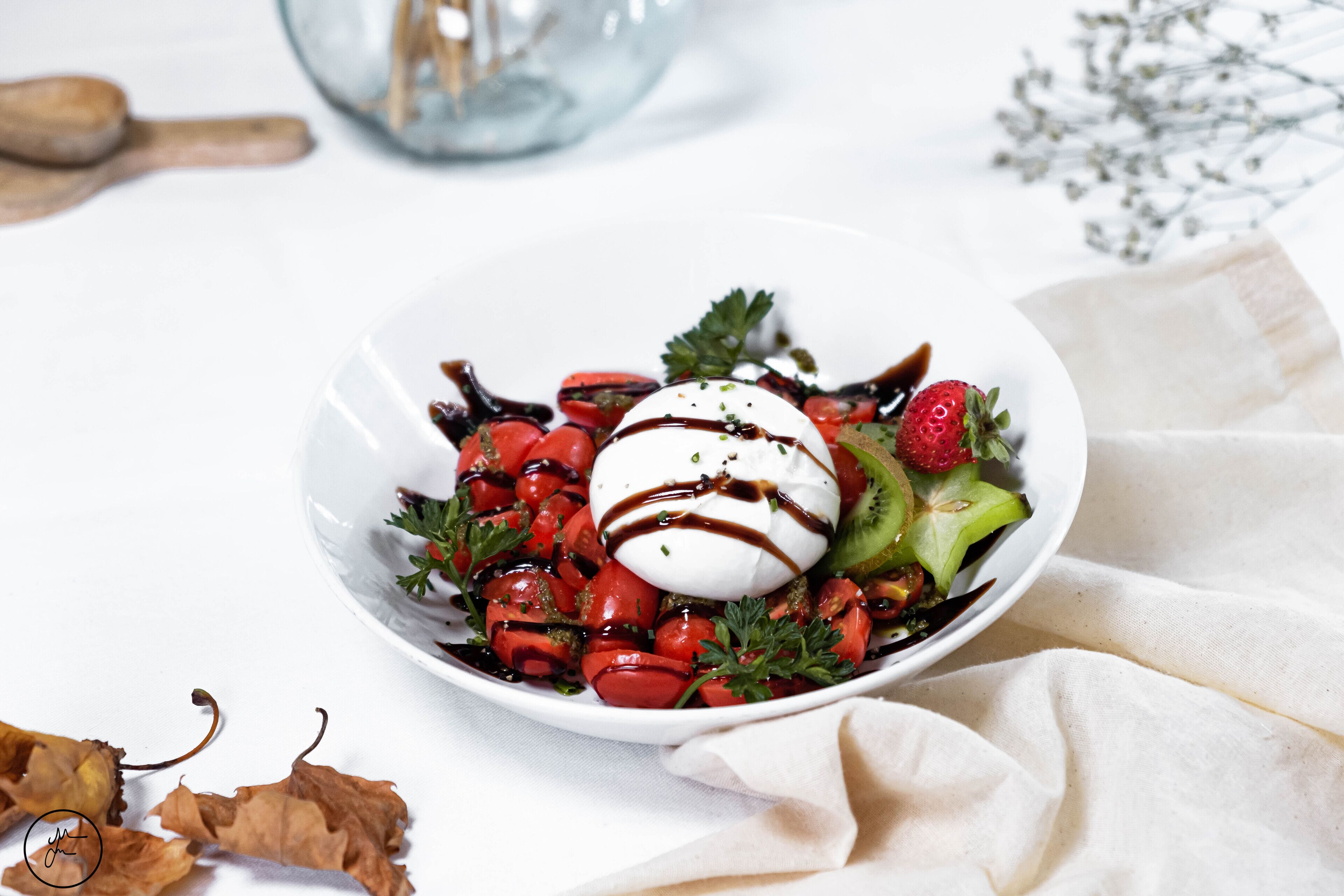 A white plate with a salad, a dollop of cream, and a drizzle of sauce.