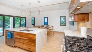 Una cocina moderna con una isla central, armarios de madera, electrodomésticos de acero inoxidable e iluminación colgante.