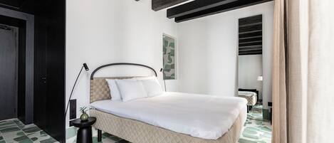 A modern bedroom with a bed, a small table with a plant, and a unique green and white patterned floor.