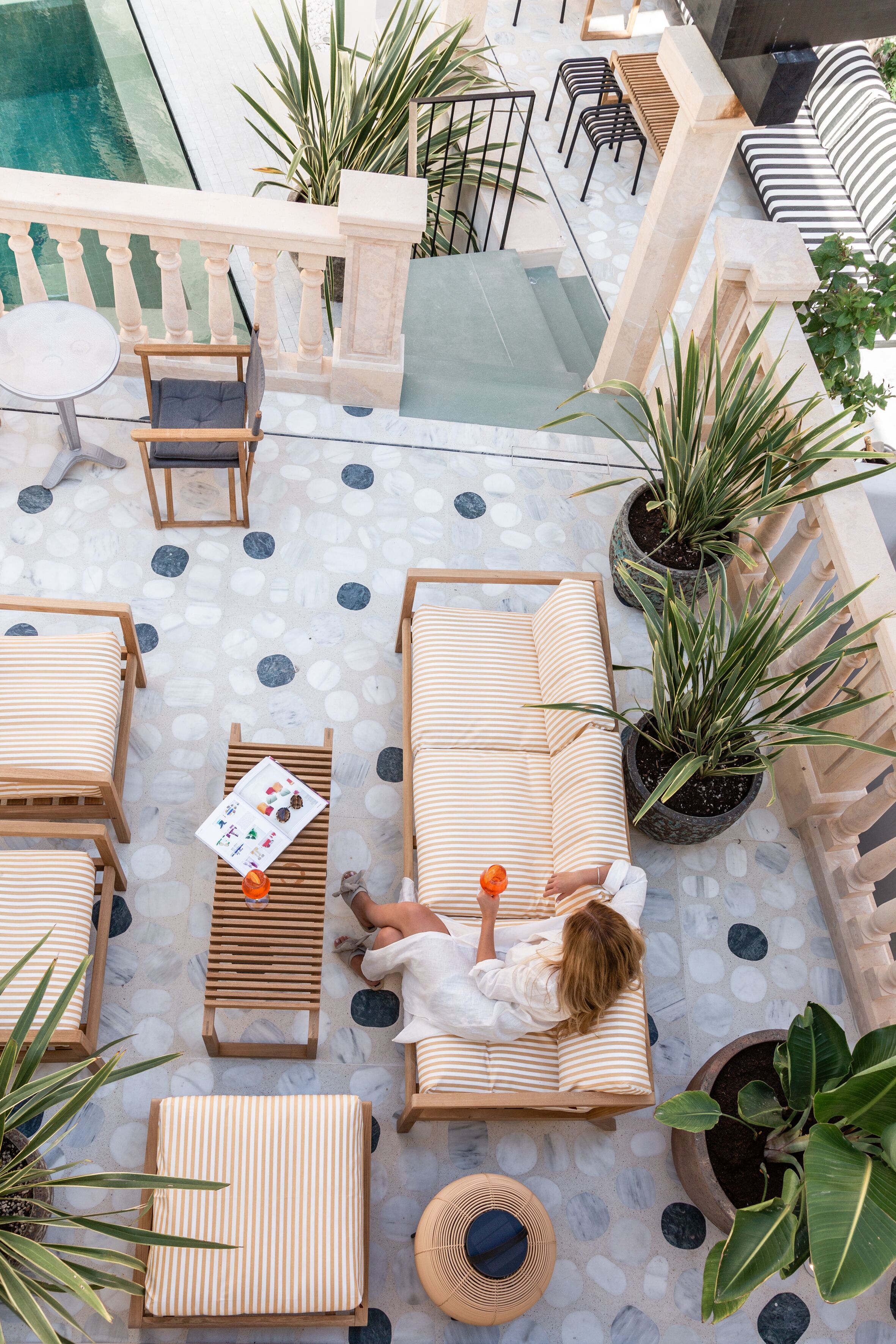Una terraza en la azotea con sillones de descanso, piscina y plantas en macetas.