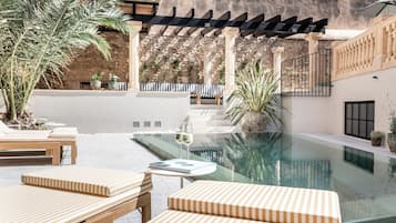 Una piscina al aire libre, sombrillas, tumbonas