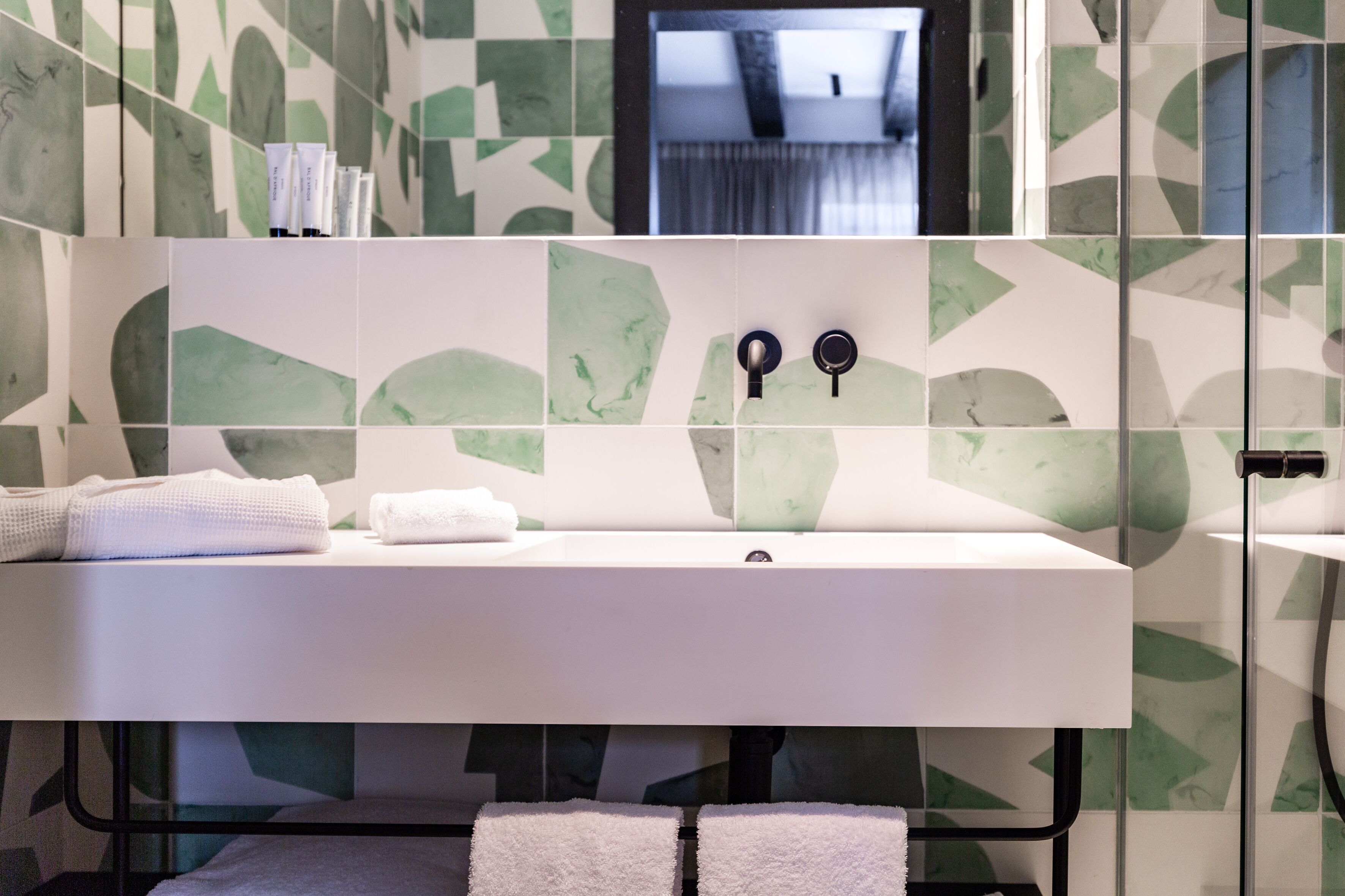 A bathroom with a white sink, two black faucets, and a mirror above it.