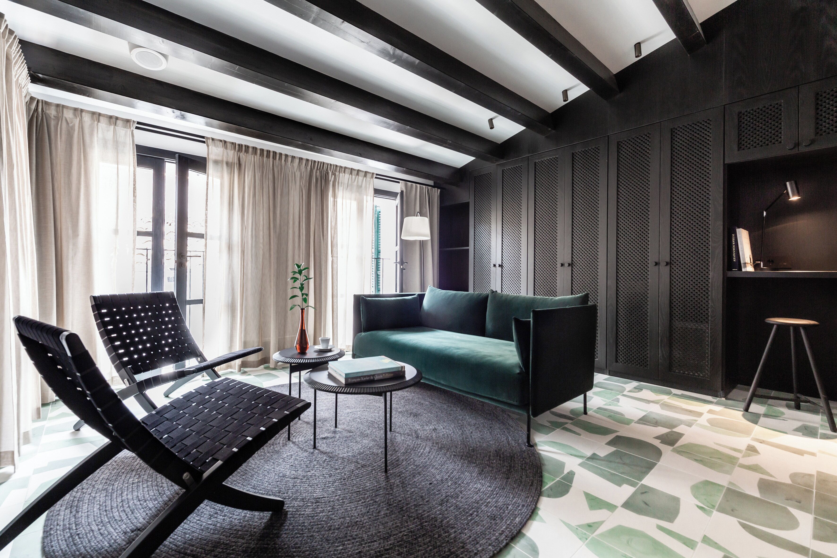 Een moderne woonkamer met een zwarte fauteuil, een groene bank en een ronde salontafel.